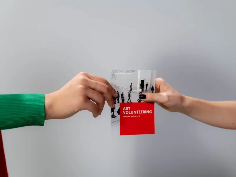 A promotional flyer being exchanged between two people — exactly the arm's-length scan distance QR codes on flyers need to survive.