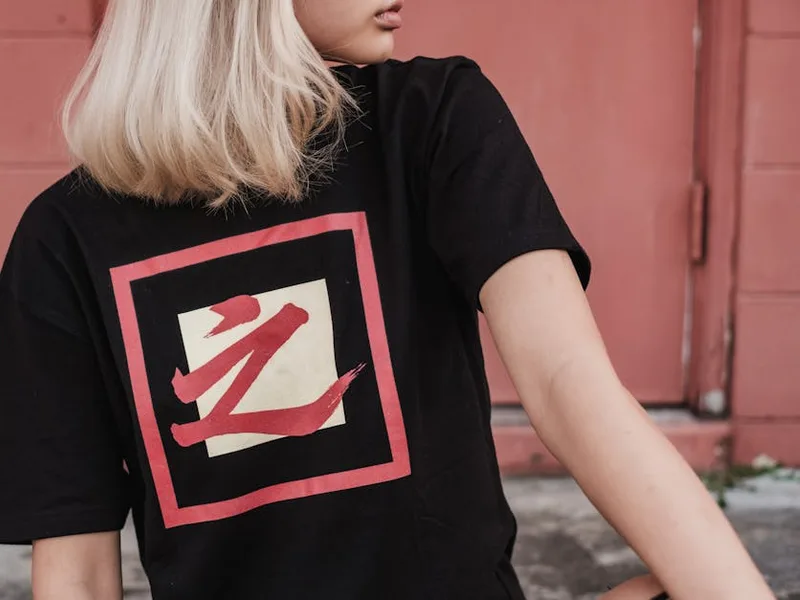 A woman wearing a black t-shirt with a modern graphic design — the exact context for a QR on apparel: textured fabric, body movement, wash cycles.